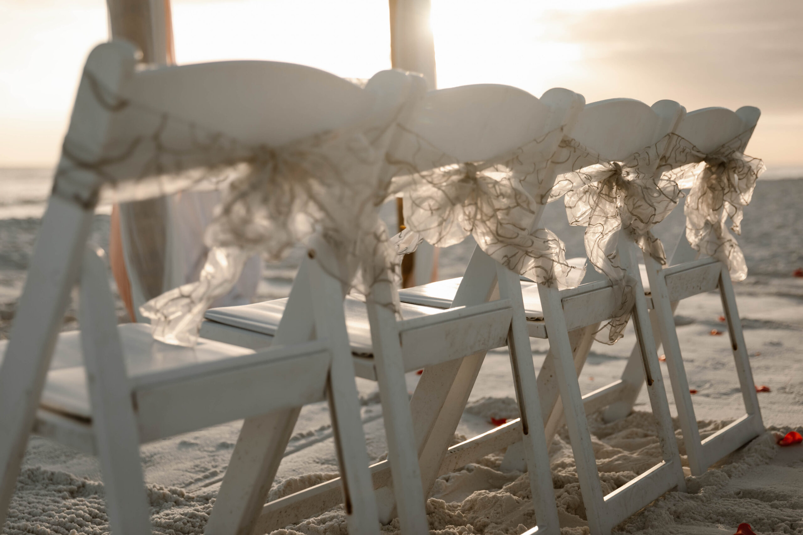 Ceremony chairs with sashes on the beach at sunset in Destin, Florida