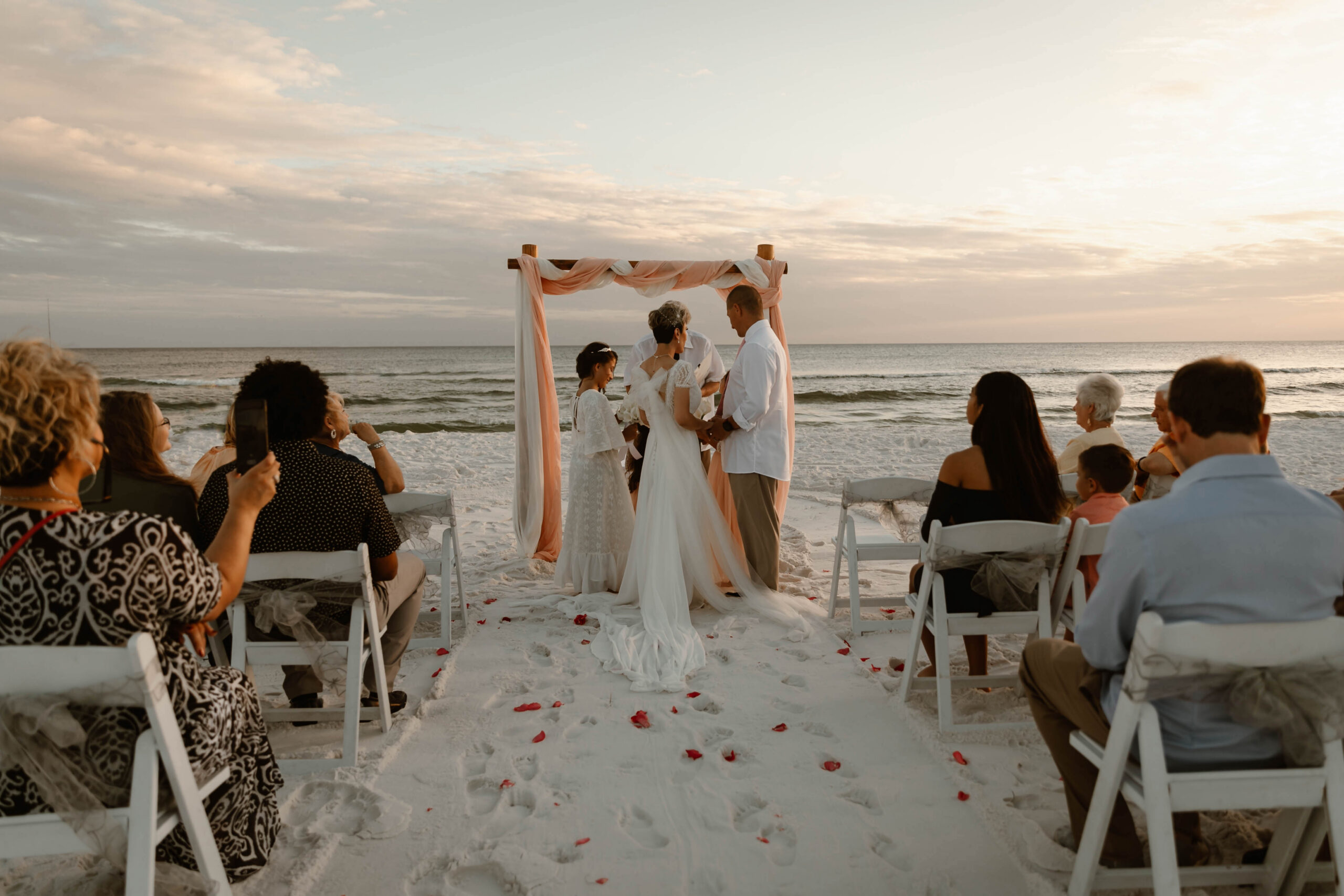 sunset ceremony under a draped arbor on the white sand at a Destin beach elopement