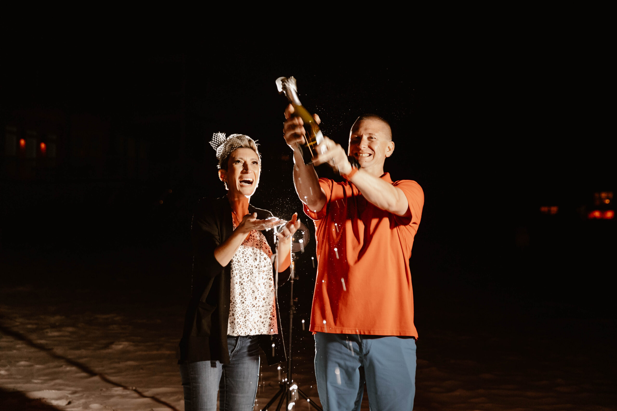 Couple popping champagne at their beach bonfire celebration in Santa Rosa Beach